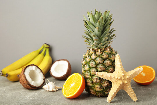 Tropical fruits. Pineapple, coconut, orange and banana on grey background
