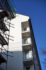 Wohnhaus mit Eckbalkon und sanierter Fassade und Altbau mit Baugerüst vor blauem Himmel im Sonnenschein im Stadtteil Bornheim in Frankfurt am Main in Hessen