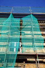 Sanierung eines Altbau und Wohnhaus mit Baugerüst und Schutznetz in Grün vor blauem Himmel im...