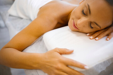 Obraz na płótnie Canvas Restorative Repose: Youthful Woman Finding Peace on Massage Bed
