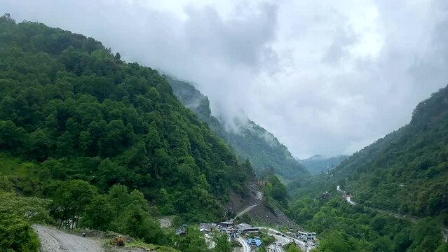 Storm clouds over mountains of Jang town deep in the  jang valley in tawang district of arunachal pradesh and surrounded by high mountains on a bright morning rainy day in arunachal pradesh in India.