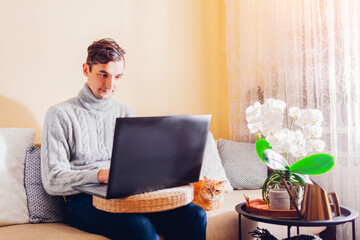 Man working online from home with pet using laptop. Freelancer typing on computer sitting on couch. Remote job