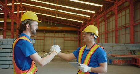 Two smiling construction workers in safety gear high-five, celebrating teamwork and successful...