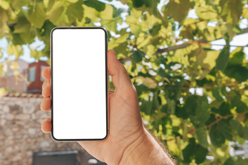 Man holding smartphone with blank white mockup screen in house back yard