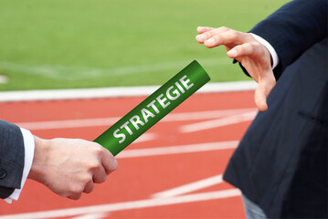 Businessmen pass baton with German word Strategie means Strategy in rely race in stadium