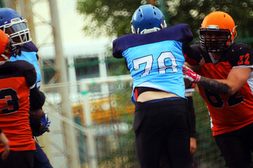 An American football player in an orange and black uniform with the number 32 grabs an opponent...
