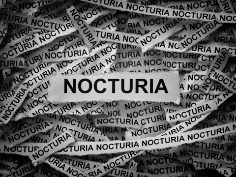 Strips of newspaper with the words Nocturia typed on them. Black and white. Close up.