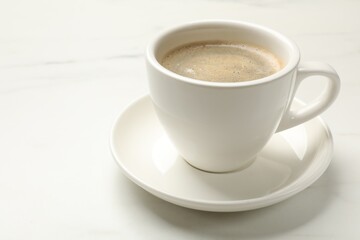 Cup of aromatic coffee on white table, closeup. Space for text
