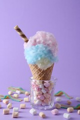 Sweet cotton candy in waffle cone and marshmallows on purple background