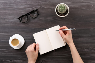 Woman with notebook and pen at grey wooden table, top view. Space for text