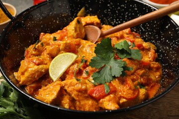 Delicious chicken curry in frying pan on table, closeup