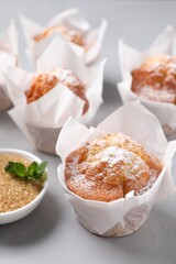 Delicious muffins with powdered sugar on grey table, closeup