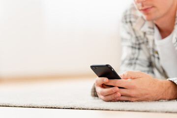 Close-up of an unrecognizable young man using phone lying at home