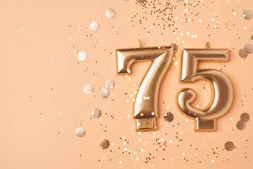75 years celebration. Greeting banner. Gold candles in the form of number seventy five on peach...