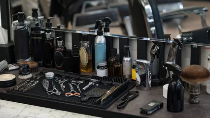 Tuinposter Barbers tools for mens haircuts laid out on a table. Men's hair and beard care products. © Niko_Dali