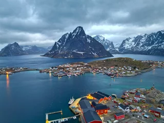 Selbstklebende Tapeten Reinefjorden Aerial view of Lofoten island Norway. The winter season of sunrise fishing village of Reine with snowscape mountain peak reflect on water. Norway with red rorbu houses. With falling snow in winter.