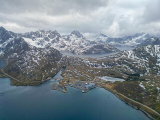 Breathtaking aerial view of a village nestled between snowy mountains and a fjord in Lofoten, Norway