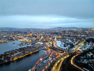 Fototapeta na wymiar Top aerial view of Oslo city in Norway at evening time. Panorama view of city with modern architecture and transportation. The fjord city with seashore and icebergs. The lighting time of capital city.