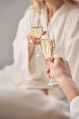 Romantic couple with a glass of champagne sat on large bed