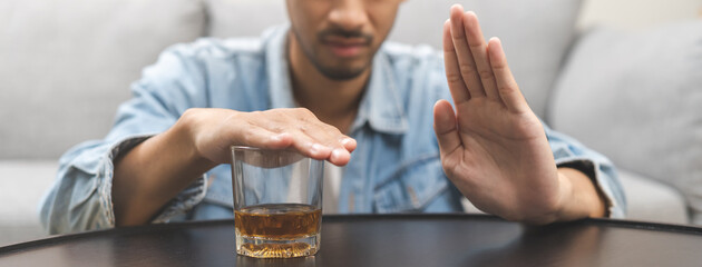 Alcoholism, depressed asian young man refuse, push out alcoholic beverage glass, drink whiskey, sitting alone at night. Treatment of alcohol addiction, having suffer abuse problem alcoholism concept. - obrazy, fototapety, plakaty