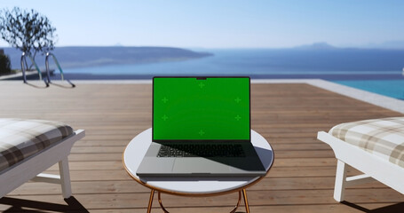 Swimming pool with beach lounge chair sun bed on the wooden deck and sea view. Laptop place on table, Green screen display, Close up monitor of notebook with mock up