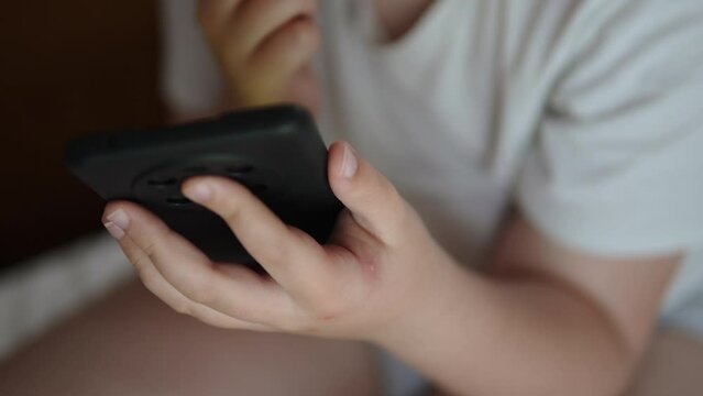 Blisters from bites on delicate light skin of unrecognizable child, close-up. Boy hands after being bitten by bed bugs plays on smartphone. Harmful domestic insects, allergic reaction.