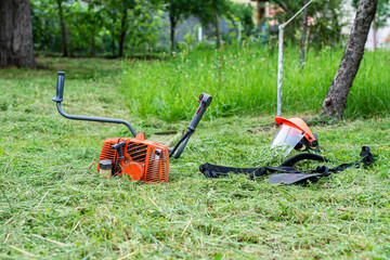 String trimmer and protective face mask on mown grass.