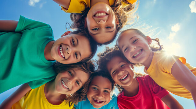 High-angle shot of a group of children forming a circle and looking up towards the camera with smiling faces.