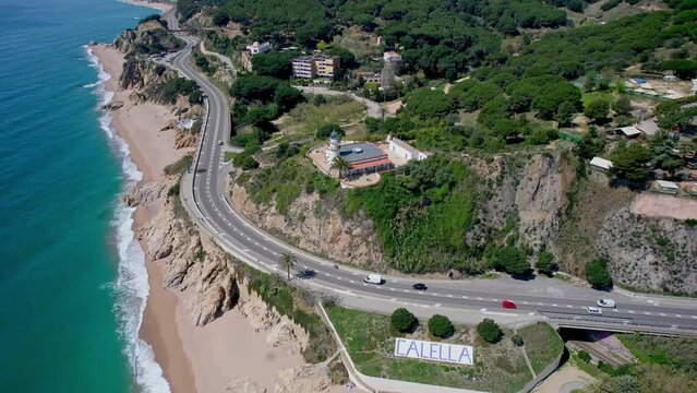 V&iacute;deo a&eacute;reo con dron de un faro sobre una monta&ntilde;a frente a una playa. Hermosa vista del mar y balneario de la costa de Barcelona