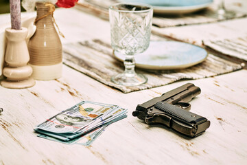 A gun, money and a glass of wine on a table in a restaurant, cafe
