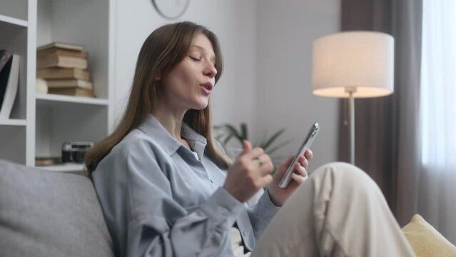Portrait of beautiful young woman having video call conference meeting by smartphone laying on couch at home Smiling confident female talking on personal conversation Distance relationships