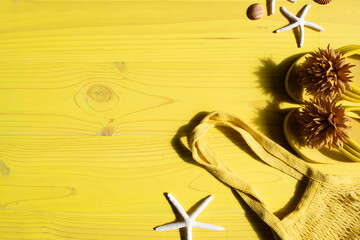 Concept summer vacation beach creating composition with starfishes, beach bag, flip flop on yellow...