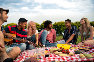 Group of multiethnic teenagers spending time outdoor on a picnic at the park