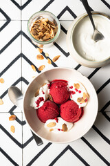 photographie culinaire d'un bol de glace à la framboise avec des amandes effilées et de la chantilly