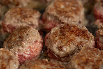 Meat balls are fried in a frying pan in vegetable oil