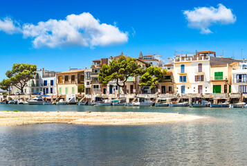 Fototapeta premium Line of houses with boats at the port of Portocolom with a sandbank in front - 8457