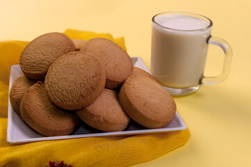 Cookies and a cup of milk on a yellow tablecloth