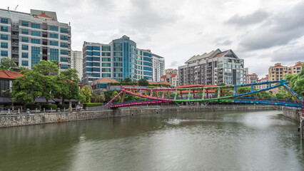 Fototapeta na wymiar Alkaff Bridge on the Singapore River at Robertson Quay with dark gray clouds timelapse hyperlapse