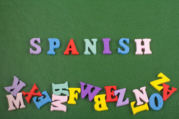 SPANISH word on green background composed from colorful abc alphabet block wooden letters, copy...
