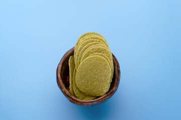 Avocado chips with bowl on blue background