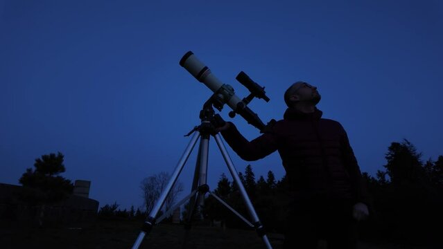 Amateur astronomer looking at the evening skies, observing planets, stars, Moon and other celestial objects with a telescope.	
