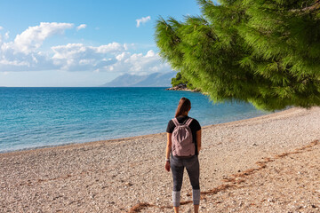 Hiker woman on idyllic stone beach in coastal town Makarska, Dalmatia, South Croatia, Europe....