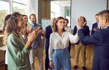 Team of happy business people celebrating success together. Group of men and women having fun at...