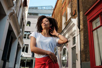 Naklejka na ściany i meble Black woman model posing in a narrow street.