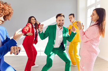 Group of happy, cheerful young friends in colorful green, red, yellow, pink, blue suits having a...