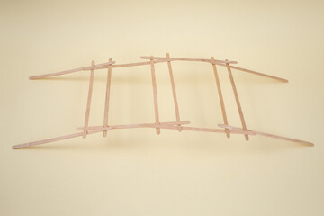 Self supporting structure for a bridge explained with bamboo sticks on beige background, abstract...