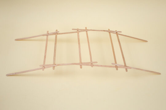 Self supporting structure for a bridge explained with bamboo sticks on beige background, abstract concept