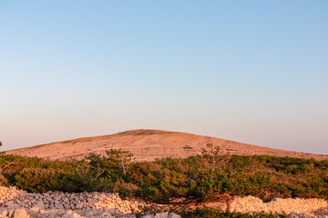 Fototapeta premium Idyllic hiking trail on plateau to the moon with scenic view of mountain peak Hlam near Baska, Krk Island, Primorje-Gorski Kotar, Croatia, Europe. Deserted barren rock landscape on sunny summer day