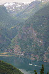 view of a Norwegian mountain river with clear blue water, on which a white private yacht moves.