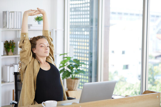 businesswoman doing exercise and two arm stretches after finishing work in the office